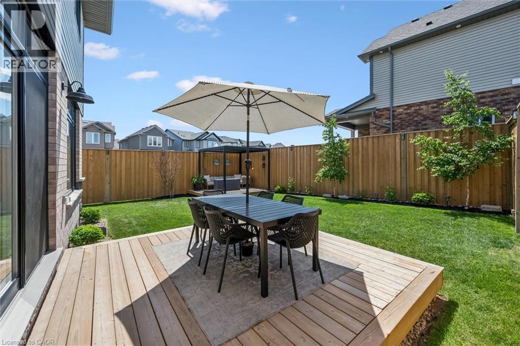 Expansive backyard featuring a large wood deck, manicured lawn, and privacy fencing - 30 Waterbow Trail, Kitchener, ON - Outdoor With Deck Patio Veranda
