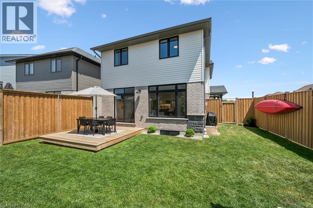 Modern rear exterior featuring a raised wooden deck, full-height windows, a full-lite glass door, and a private wooden fence - 30 Waterbow Trail, Kitchener, ON - Outdoor With Deck Patio Veranda