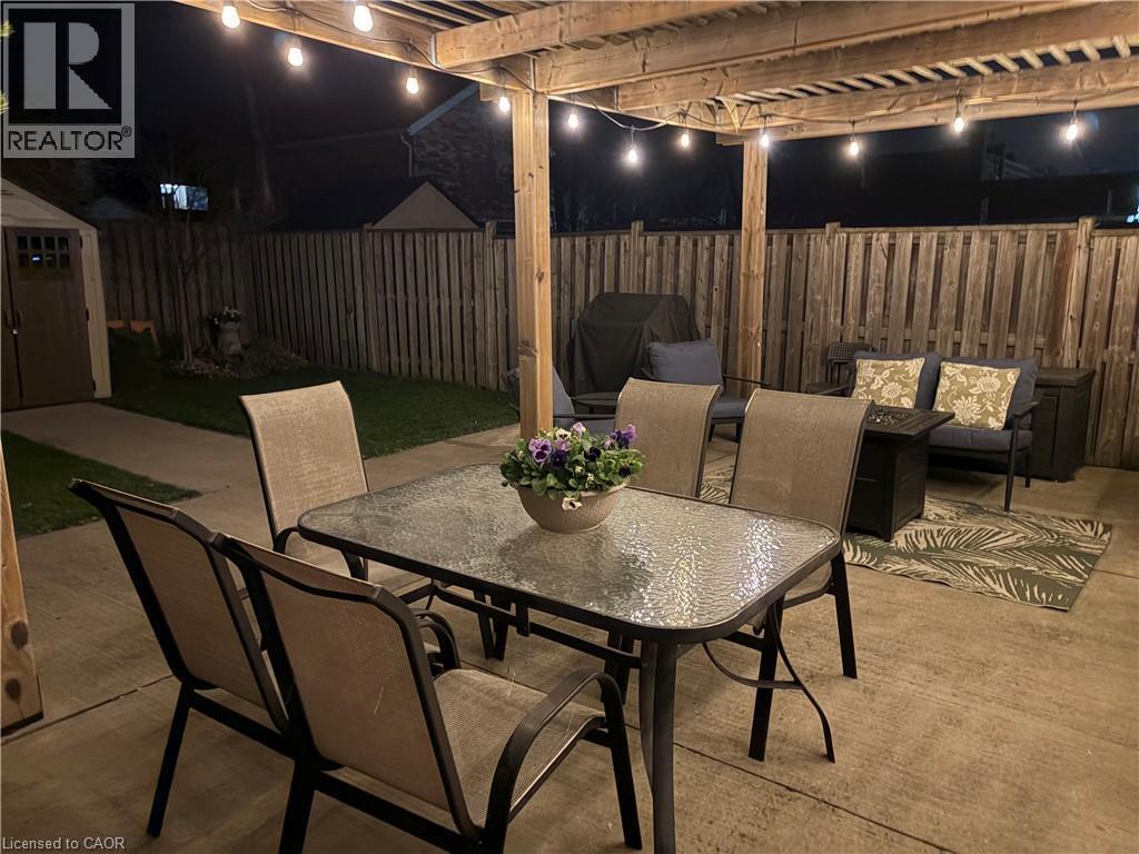 The property features a concrete patio area with a wooden pergola, equipped with string lights - 153 Elgin Street, Hamilton, ON