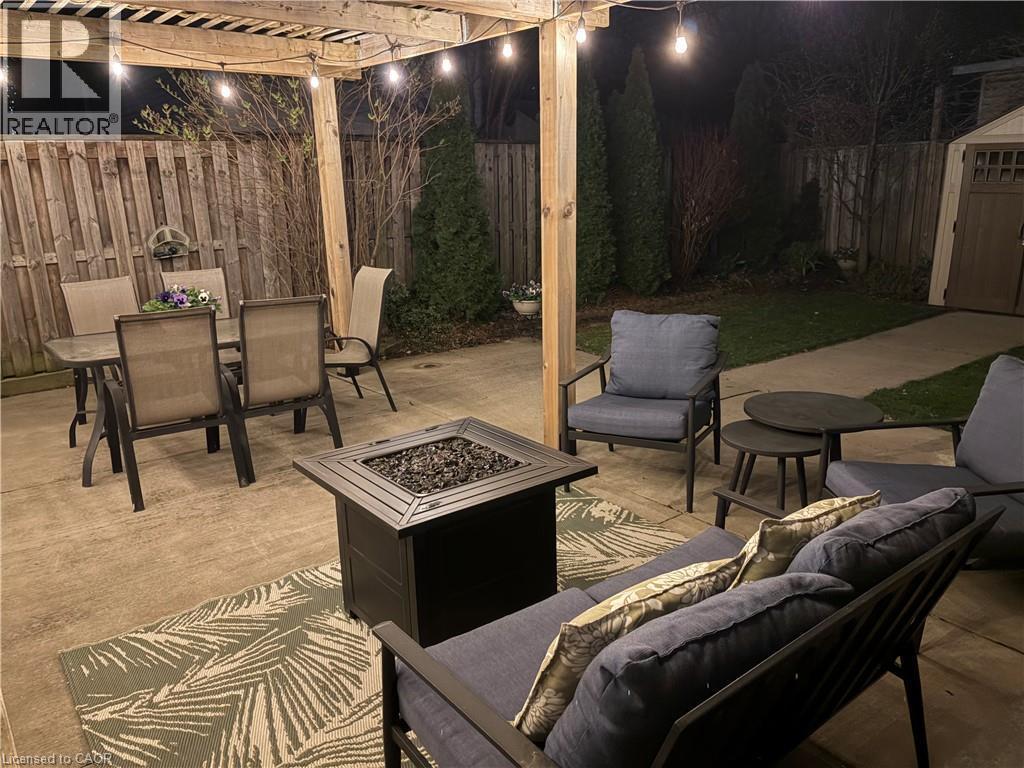 The patio features a pergola with string lights, a fire pit, and a concrete surface - 153 Elgin Street, Hamilton, ON