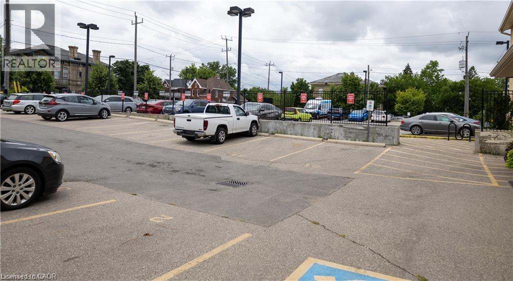 Paved parking lot with marked spaces, security fencing, and exterior lighting fixtures - 365 Colborne Street, Brantford, ON