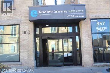Brick facade building featuring a prominent main entrance with automatic glass doors, a large modern awning, and expansive storefront windows - 365 Colborne Street, Brantford, ON