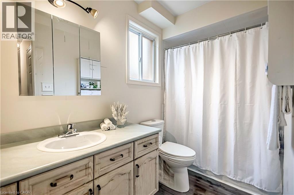 Bathroom featuring a vanity with a white oval sink, a light-toned countertop, and distressed-finish cabinetry - 640 Acadia Drive, Hamilton, ON