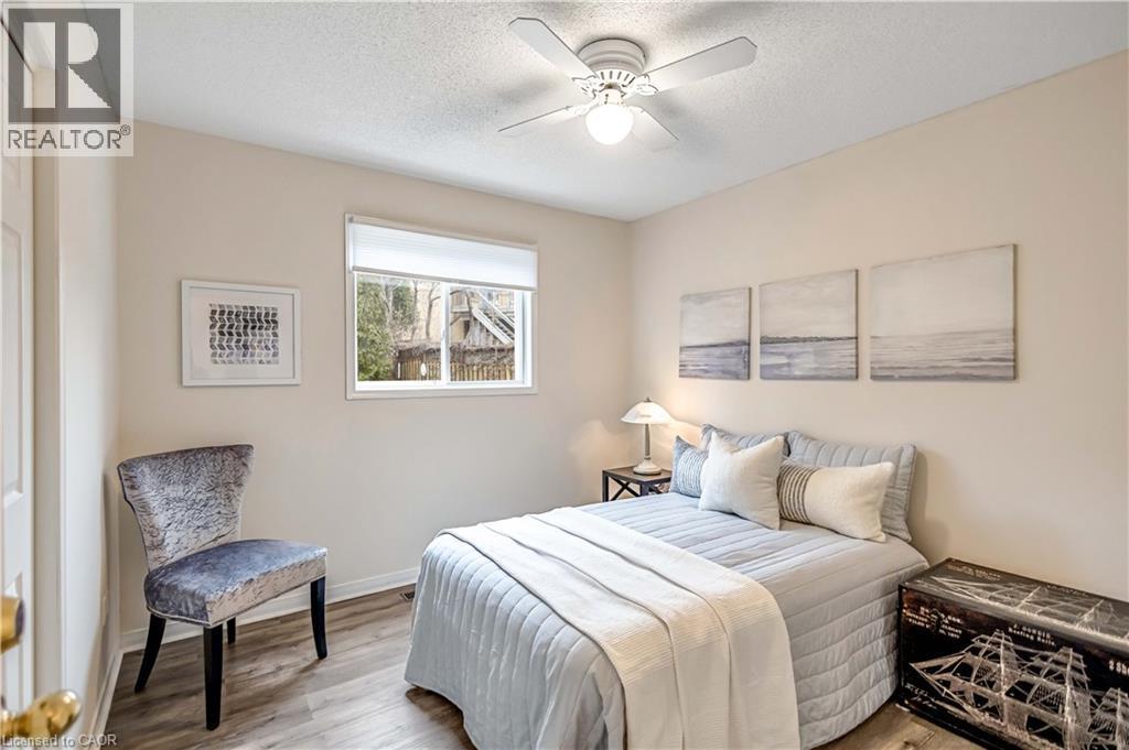 Bedroom featuring wood-finish flooring, a double window, and a ceiling fan with integrated lighting - 640 Acadia Drive, Hamilton, ON