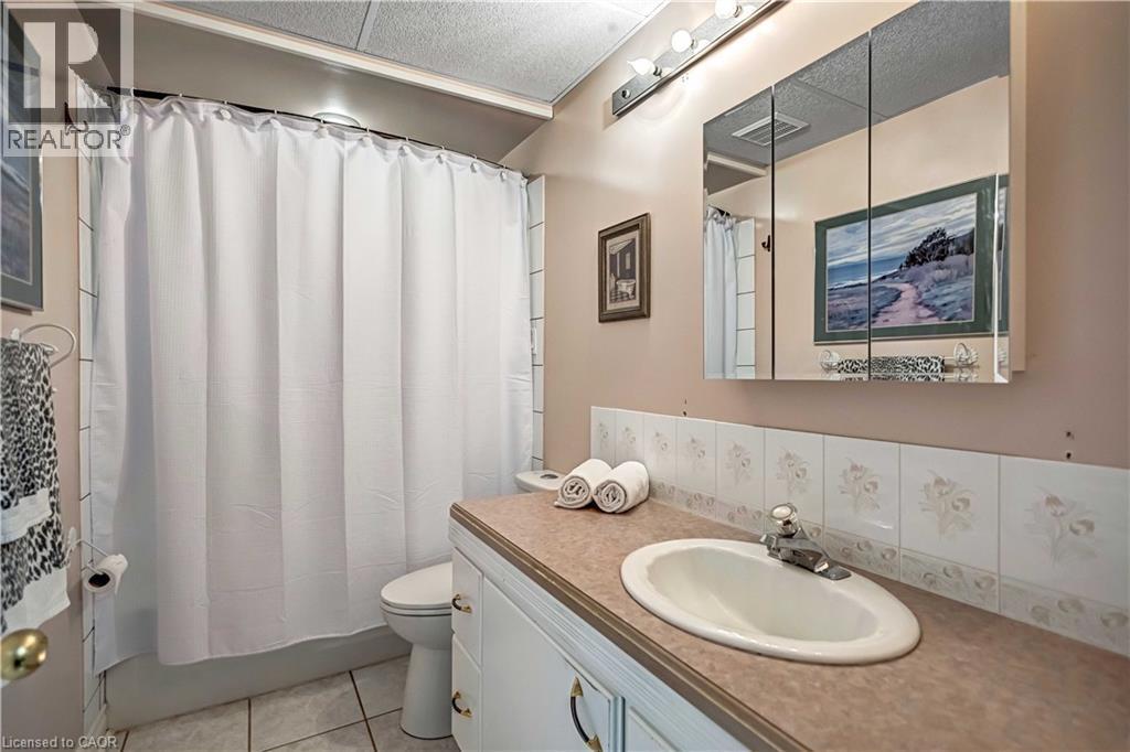 Bathroom featuring a vanity with an integrated sink, a medicine cabinet, a full bathtub with shower, and tiled flooring - 640 Acadia Drive, Hamilton, ON
