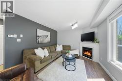 Living area featuring wood-finish flooring, a white trim window, and a corner fireplace with a white mantel -