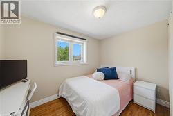 Bedroom with wood-finish flooring, neutral wall paint, and a white ceiling -