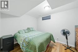 Recessed ceiling light fixture illuminating a room with wood-finish flooring, a white wall, and a horizontal window with a dark blind -
