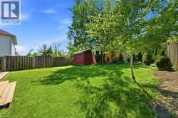 Expansive backyard featuring a manicured lawn, established trees, and a wooden privacy fence -