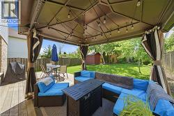 Spacious outdoor deck featuring a large gazebo with string lighting, privacy curtains, and a built-in outdoor kitchen area -