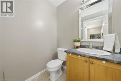 Powder room featuring a single vanity with a laminate countertop, an undermount sink, and a framed mirror -
