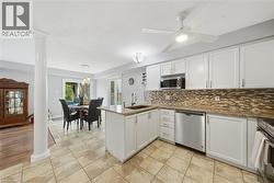 Bright kitchen featuring white shaker cabinetry, granite countertops, stainless steel appliances, and a mosaic tile backsplash -