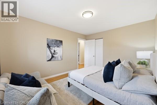 Bedroom featuring light-colored walls, wood-finish flooring, a flush-mount ceiling light fixture, and white bi-fold closet doors - 957 Stone Church Road E, Hamilton, ON - Indoor Photo Showing Bedroom