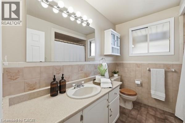 Bathroom vanity featuring a single basin, light-toned countertop, and white cabinetry - 957 Stone Church Road E, Hamilton, ON - Indoor Photo Showing Bathroom