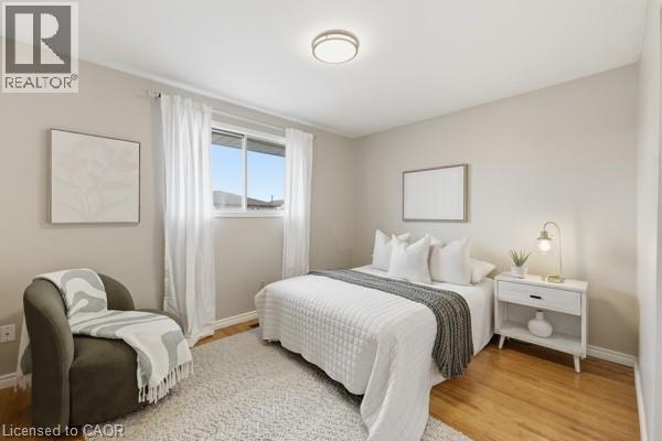 Hardwood flooring featuring a window with white drapes, neutral wall paint, and a ceiling-mounted light fixture - 957 Stone Church Road E, Hamilton, ON - Indoor Photo Showing Bedroom
