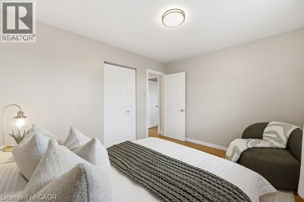 Bedroom featuring neutral wall paint, wood-finish flooring, a bi-fold closet door, a paneled interior door, and a flush-mount ceiling light fixture - 957 Stone Church Road E, Hamilton, ON - Indoor Photo Showing Bedroom