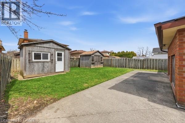 Spacious backyard featuring a substantial paved area, a manicured lawn, and two integrated storage sheds - 957 Stone Church Road E, Hamilton, ON - Outdoor