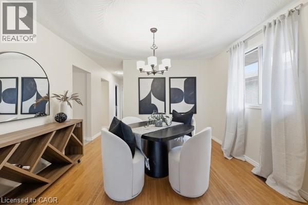 Dining area featuring hardwood flooring, a multi-light chandelier, a large window with white curtains, and a built-in wood-finish console with storage - 957 Stone Church Road E, Hamilton, ON - Indoor