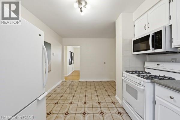 Kitchen featuring patterned tile flooring, white cabinetry, and white appliances including a refrigerator, gas range, and over-the-range microwave - 957 Stone Church Road E, Hamilton, ON - Indoor Photo Showing Kitchen