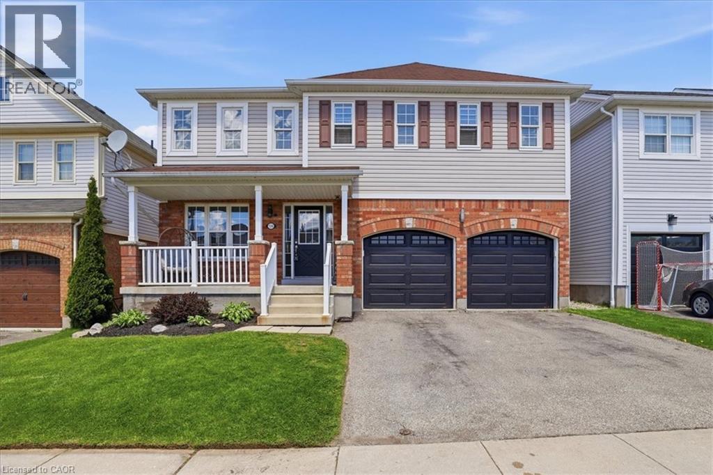 Two-story residence featuring a brick and siding facade, a covered front porch with white railings, a paved driveway, and a double-car garage with arched brick detailing - 136 Carpenter Road, Cambridge, ON - Outdoor With Deck Patio Veranda With Facade