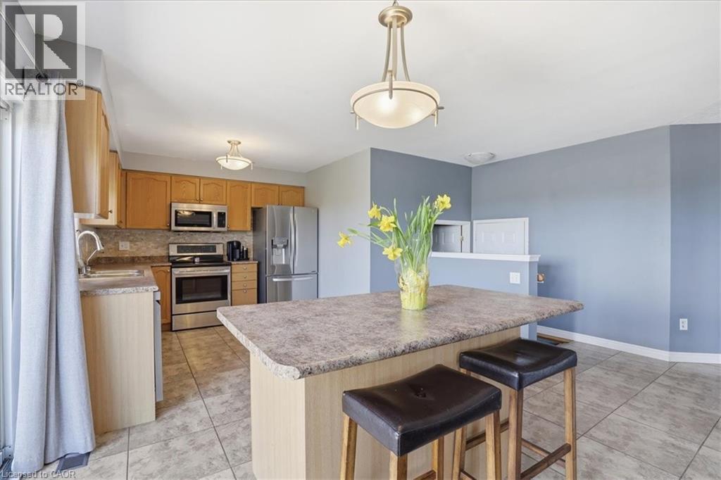 Kitchen featuring a central island with seating, stainless steel appliances, light wood-finish cabinetry, and tiled flooring - 136 Carpenter Road, Cambridge, ON - Indoor Photo Showing Kitchen With Double Sink