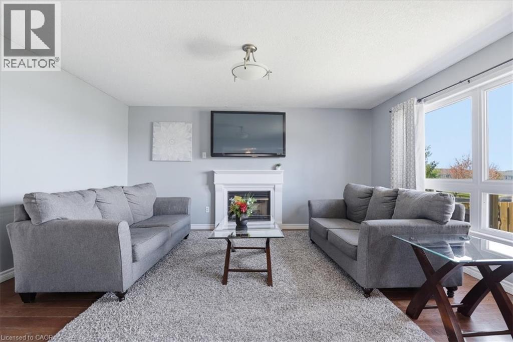 Living area featuring light gray walls, wood-finish flooring, and a central fireplace with a white mantel - 136 Carpenter Road, Cambridge, ON - Indoor Photo Showing Kitchen