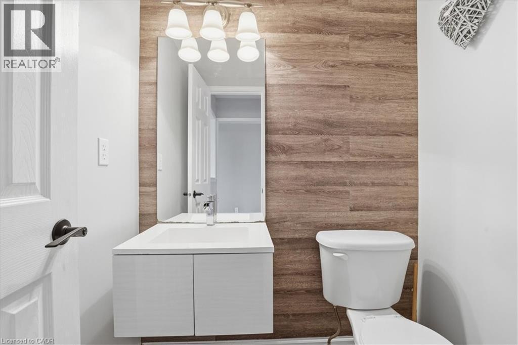 Bathroom featuring a floating vanity with an integrated sink, wood-finish accent wall, wall-mounted mirror, and vanity light fixture - 136 Carpenter Road, Cambridge, ON - Indoor Photo Showing Living Room