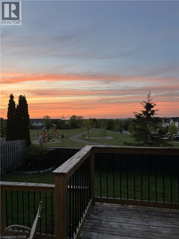 Wood deck with black metal balusters overlooking a green space with a walking path, mature trees, and a playground - 136 Carpenter Road, Cambridge, ON - Outdoor With View