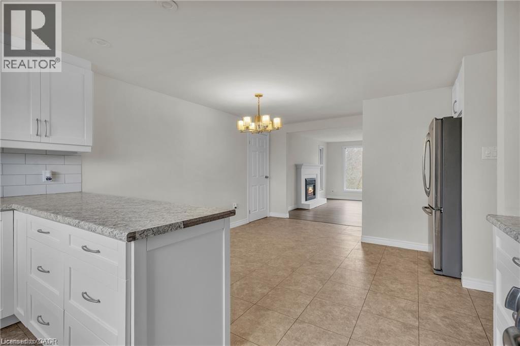 Open-concept kitchen featuring white cabinetry, granite-finish countertops, subway tile backsplash, and stainless steel appliances - 22 Blackhorne Crescent, Kitchener, ON - Indoor Photo Showing Kitchen