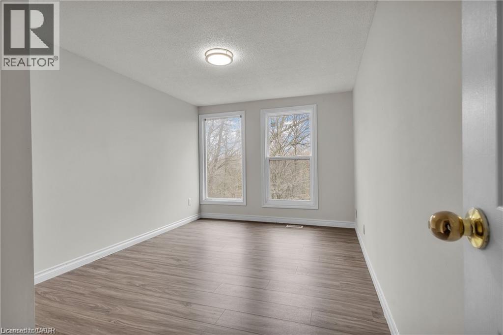 Room featuring two double-hung windows, wood-finish flooring, light grey walls, and a recessed ceiling light fixture - 22 Blackhorne Crescent, Kitchener, ON - Indoor Photo Showing Other Room