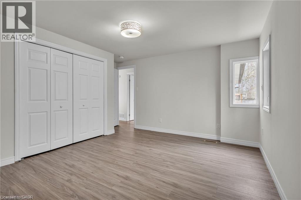 Spacious room featuring wood-finish flooring, white trim, and a contemporary ceiling light fixture - 22 Blackhorne Crescent, Kitchener, ON - Indoor Photo Showing Other Room
