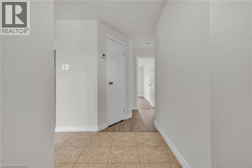 Hallway featuring neutral wall tones, white trim, and a combination of square tile flooring and wood-finish flooring - 22 Blackhorne Crescent, Kitchener, ON - Indoor Photo Showing Other Room