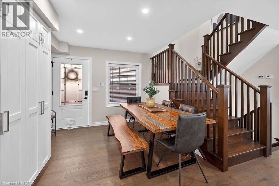Open-concept dining area featuring wood-finish flooring, recessed lighting, and a prominent wood staircase with matching balusters - 109 Ray Street N, Hamilton, ON - Indoor Photo Showing Other Room
