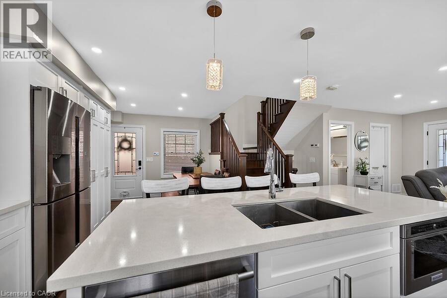 Kitchen island featuring a dual-basin stainless steel sink with a high-arc faucet, light-toned countertop, and integrated under-counter storage - 109 Ray Street N, Hamilton, ON - Indoor Photo Showing Kitchen With Double Sink With Upgraded Kitchen