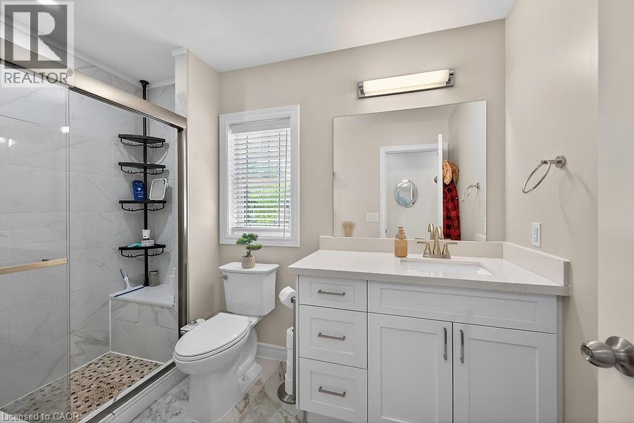 White vanity with a quartz countertop, an undermount sink, and a large wall-mounted mirror - 109 Ray Street N, Hamilton, ON - Indoor Photo Showing Bathroom