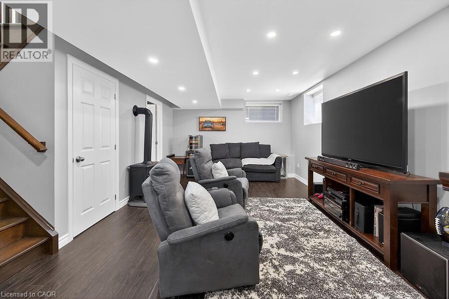Spacious room featuring wood-finish flooring, a built-in wood stove, recessed lighting, and a white panel door - 109 Ray Street N, Hamilton, ON - Indoor