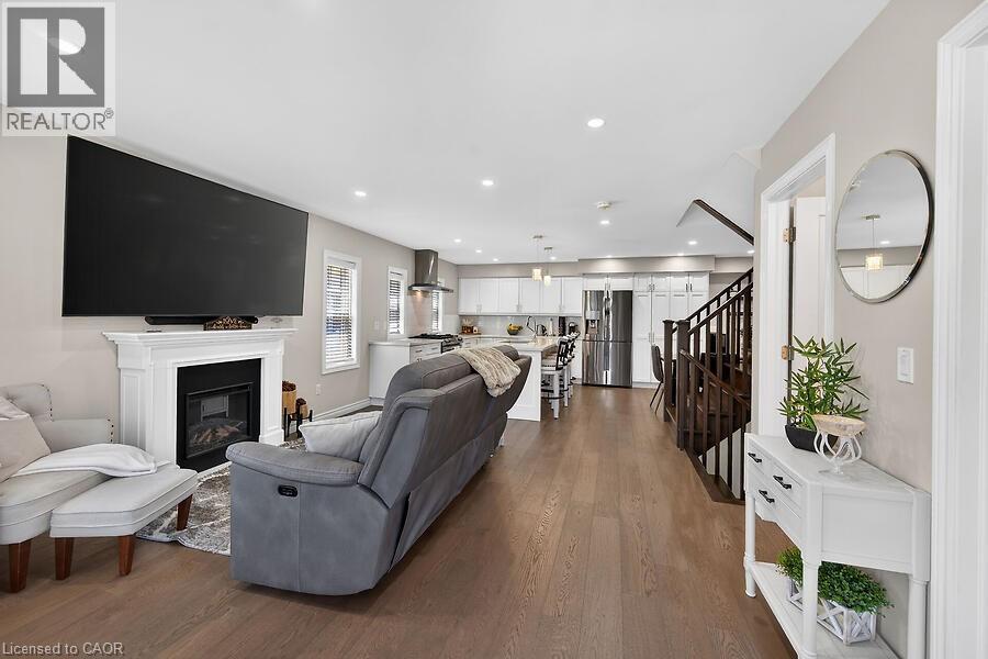 Open-concept living area featuring wood-finish flooring, a white mantel fireplace, and recessed lighting - 109 Ray Street N, Hamilton, ON - Indoor Photo Showing Living Room With Fireplace