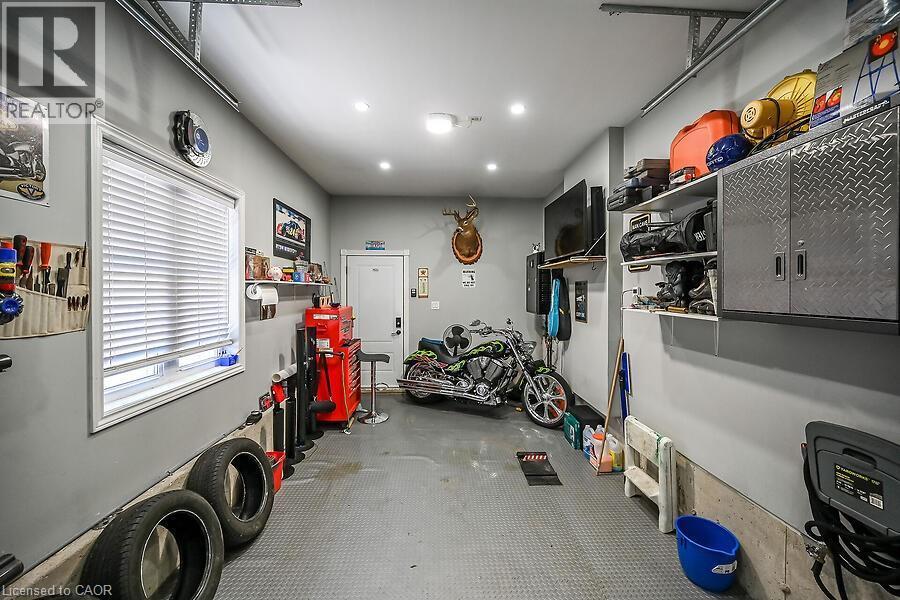 Spacious garage featuring light gray walls, a window with horizontal blinds, and a durable gray textured floor - 109 Ray Street N, Hamilton, ON - Indoor Photo Showing Garage