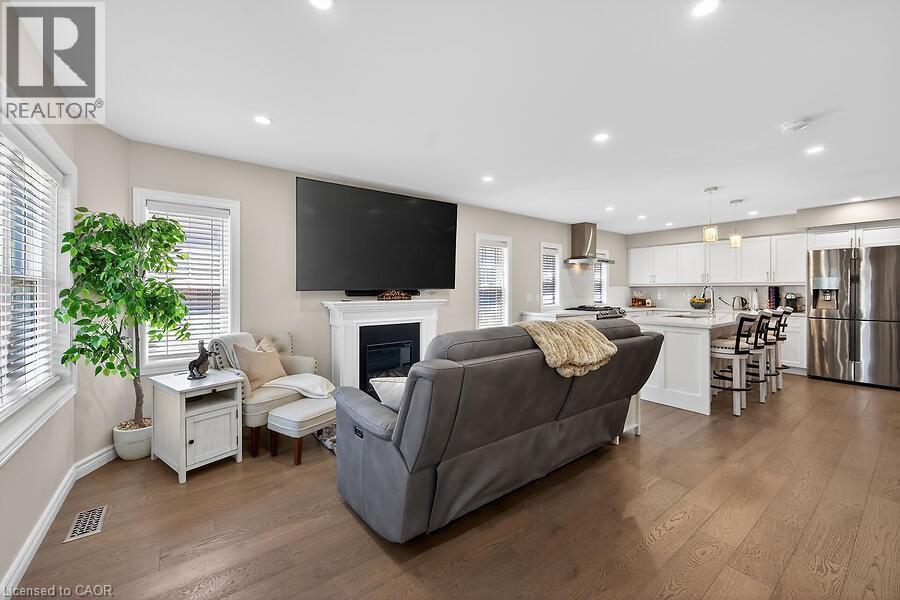 Open-concept living space featuring wood-finish flooring, a white fireplace with mantle, and recessed lighting - 109 Ray Street N, Hamilton, ON - Indoor Photo Showing Living Room With Fireplace