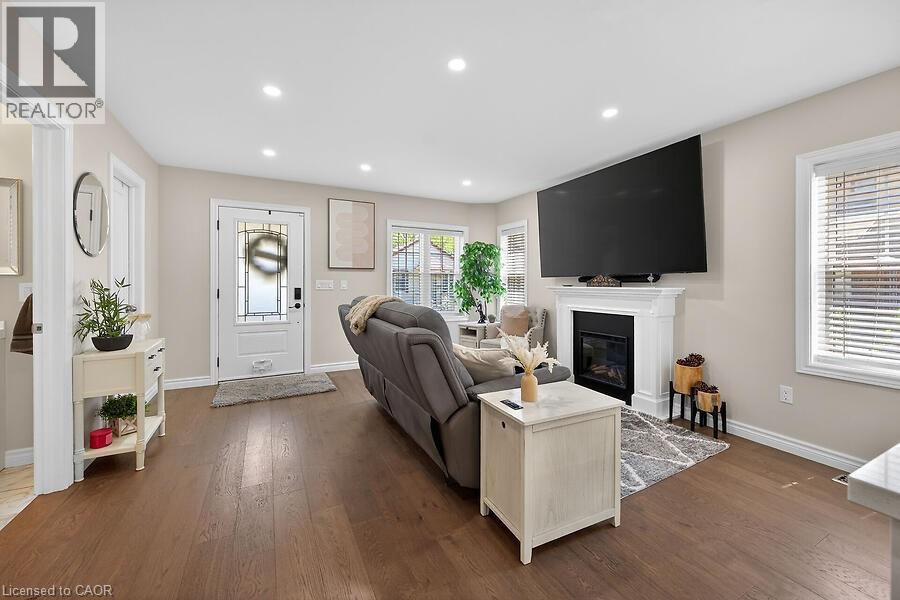 Open-concept living area featuring rich wood-finish flooring, recessed lighting, and a prominent fireplace with a classic white mantel - 109 Ray Street N, Hamilton, ON - Indoor Photo Showing Other Room With Fireplace