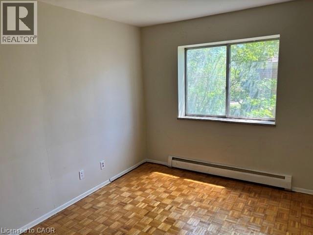Room featuring wood-finish parquet flooring, a large window, a window sill, and a baseboard heater - 2205 King Street E Unit# 1, Hamilton, ON - Indoor Photo Showing Other Room