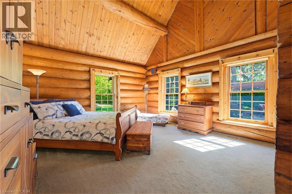 Log cabin interior featuring exposed wood log walls and a vaulted wood-paneled ceiling - 169 James Street, Atwood, ON - Indoor Photo Showing Bedroom