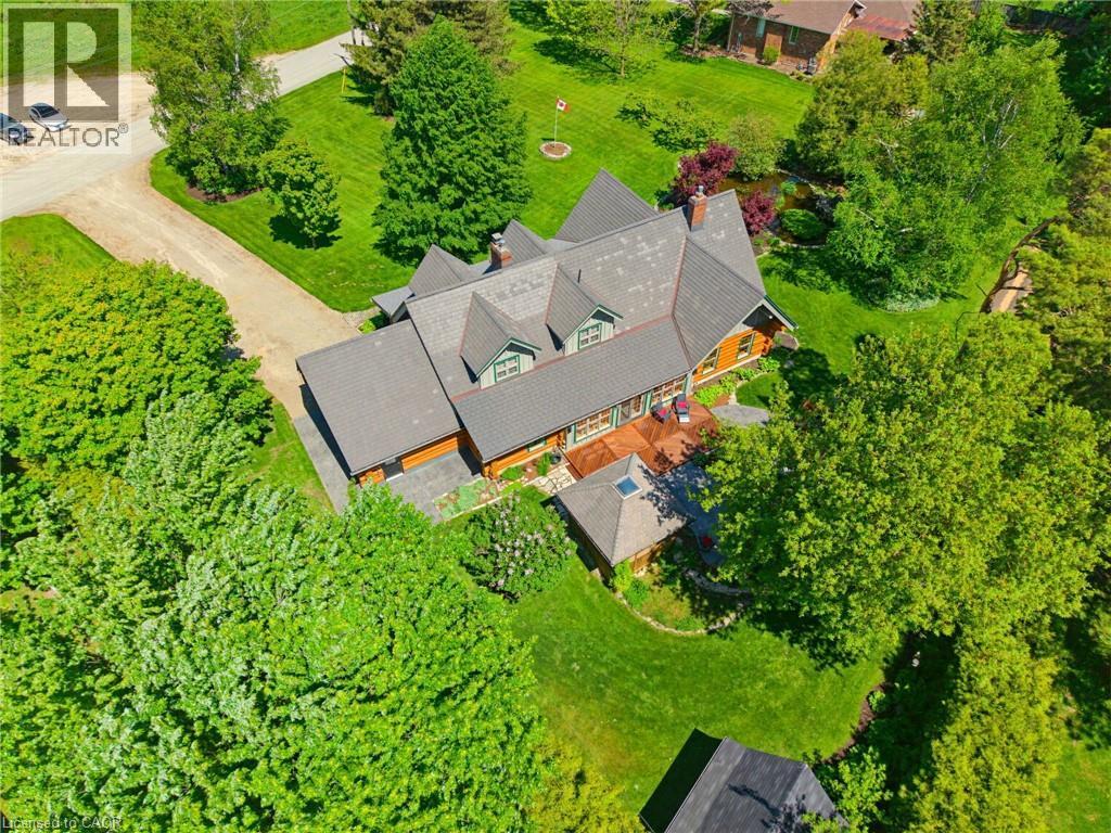 Expansive property featuring a multi-gabled roofline, a large wooden deck, and a detached structure with a skylight - 169 James Street, Atwood, ON - Outdoor