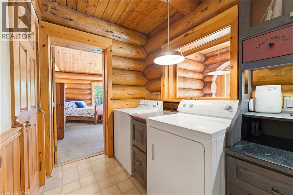 Dedicated laundry area featuring a washer and dryer, wood-finish cabinetry, a countertop surface, and log wall construction - 169 James Street, Atwood, ON - Indoor Photo Showing Laundry Room