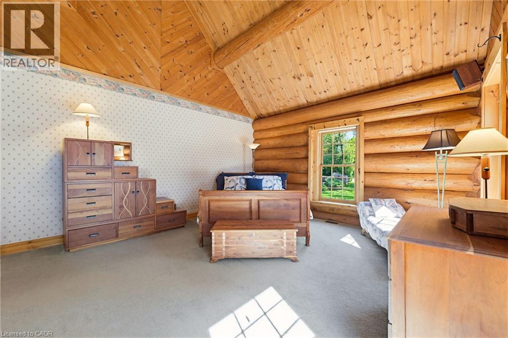 Vaulted wood-paneled ceiling with exposed beams, log wall construction, window with exterior views, and neutral carpet flooring - 169 James Street, Atwood, ON - Indoor