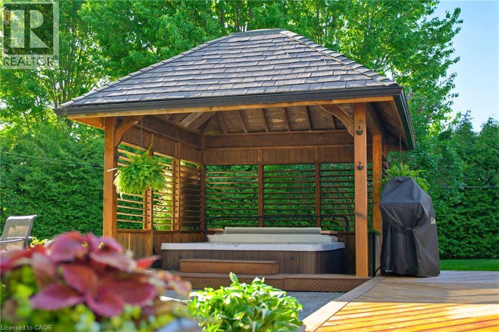 Expansive outdoor living area featuring a wooden gazebo with a shingled roof, incorporating a built-in hot tub - 169 James Street, Atwood, ON - Outdoor With Deck Patio Veranda