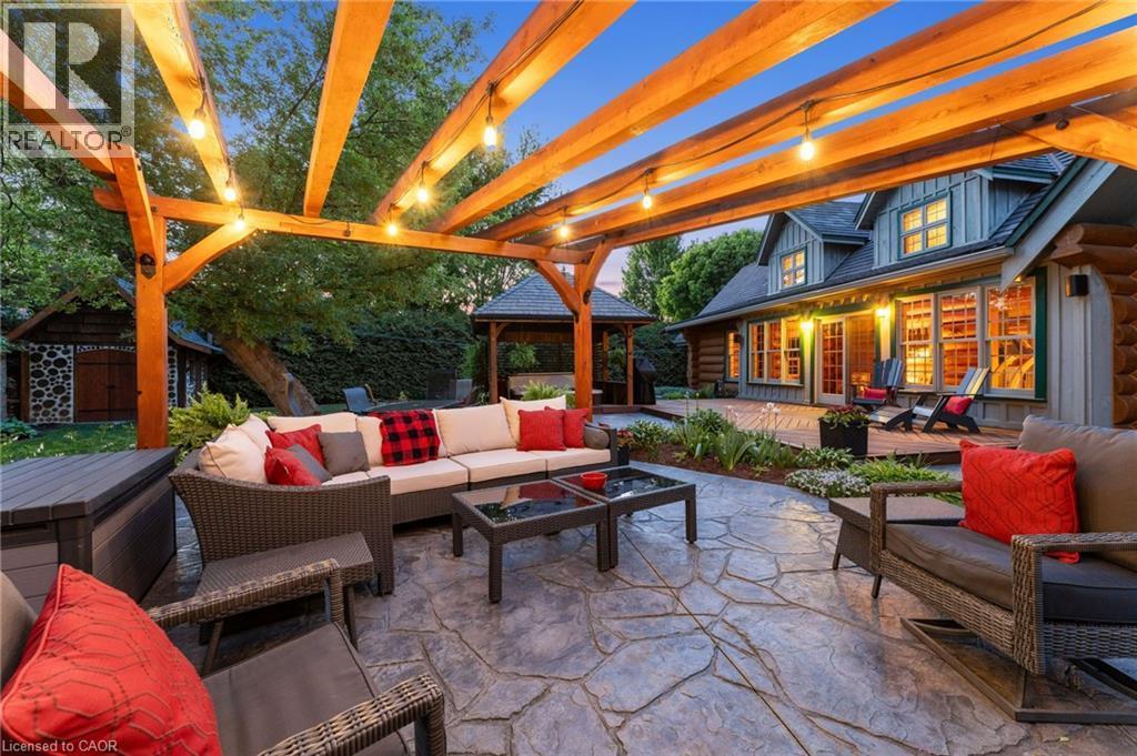 Expansive stamped concrete patio featuring a wood pergola with string lights, a built-in garden bed, and direct access to the main residence with multiple windows and a glass door - 169 James Street, Atwood, ON - Outdoor With Deck Patio Veranda With Exterior