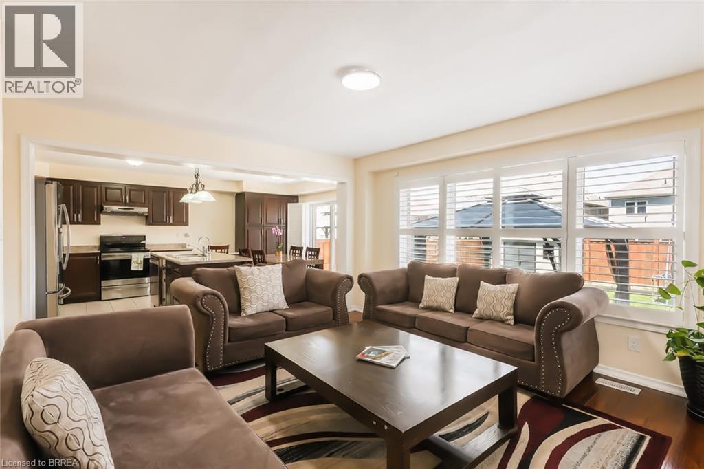 Living area featuring wood-finish flooring and a large window with white plantation shutters - 26 Pollard Street, Brantford, ON - Indoor Photo Showing Living Room
