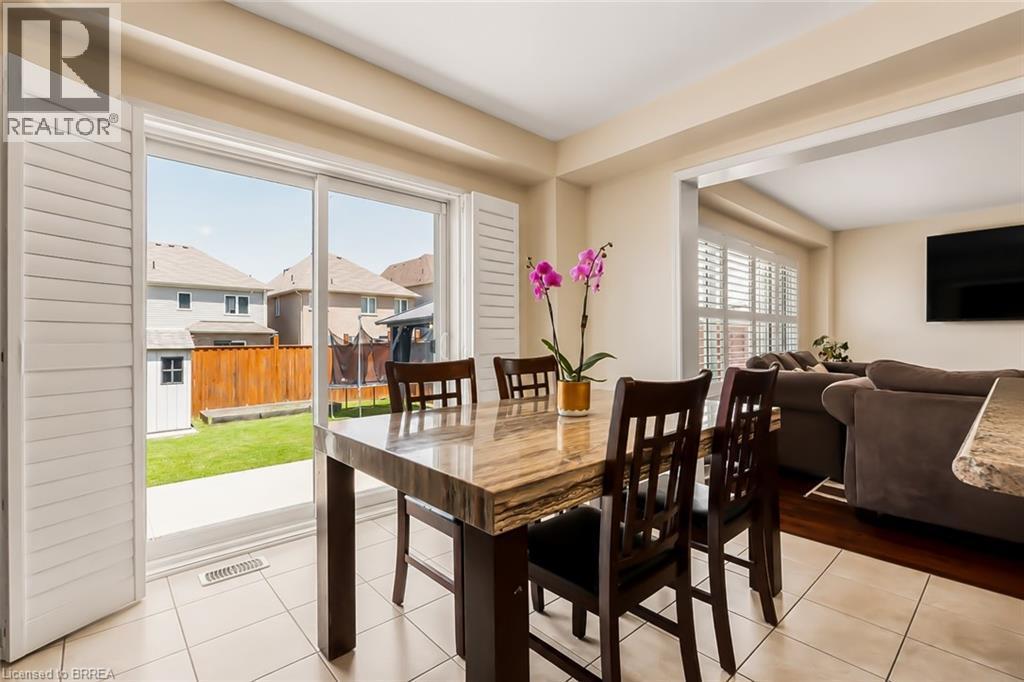 Dining area featuring a stone-look tabletop, tile flooring, and sliding glass doors with plantation shutters - 26 Pollard Street, Brantford, ON - Indoor Photo Showing Dining Room