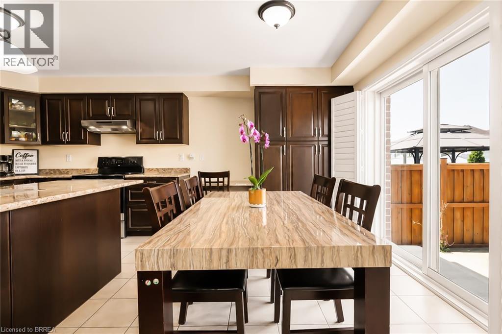Spacious kitchen and dining area with dark wood-finish cabinetry, light-toned countertops, and tile flooring - 26 Pollard Street, Brantford, ON - Indoor